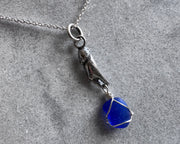 tiny crab claw holding sea glass pendant