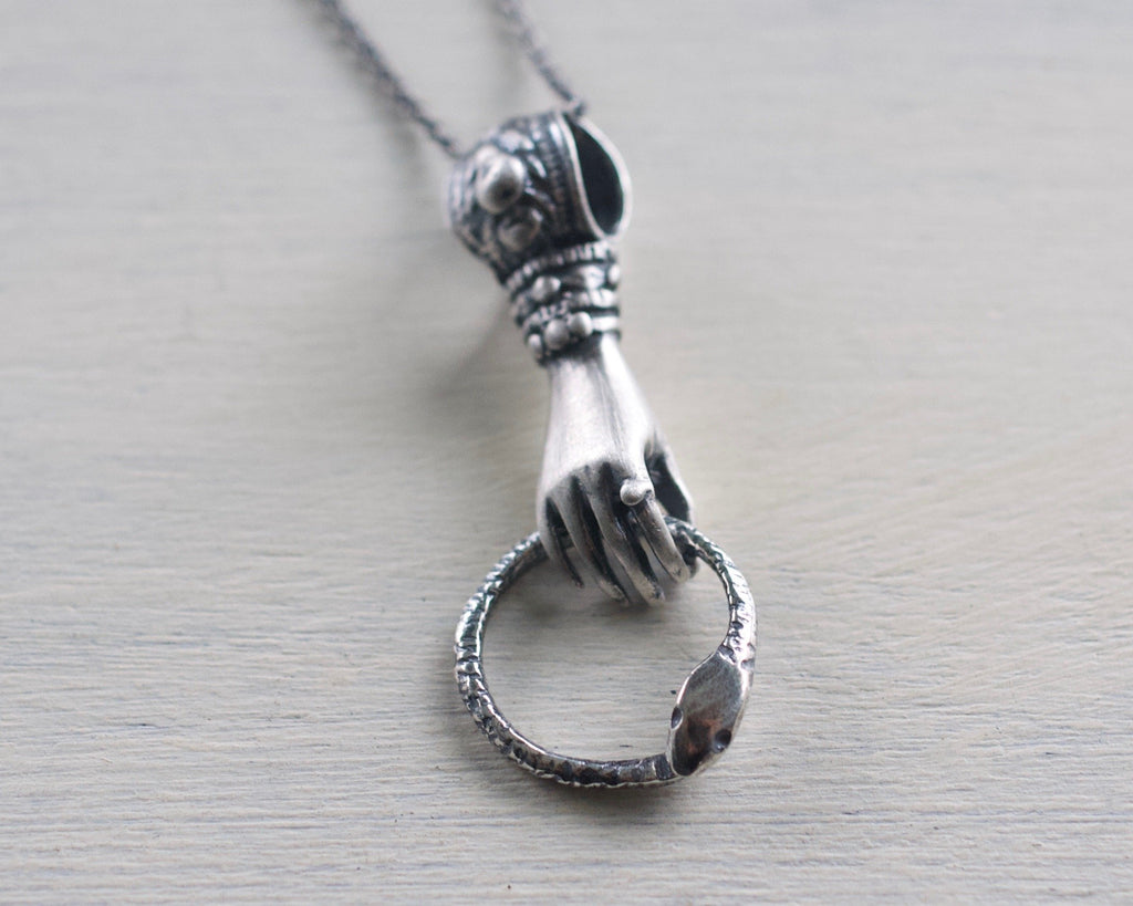 hand holding ouroboros necklace