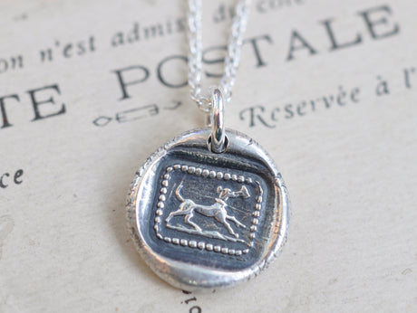 dog carrying a letter wax seal necklace