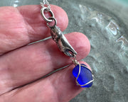 tiny crab claw holding sea glass pendant