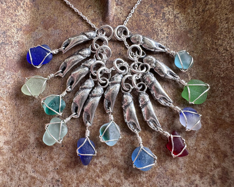 tiny crab claw holding sea glass pendant