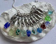 tiny crab claw holding sea glass pendant