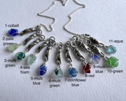 tiny crab claw holding sea glass pendant