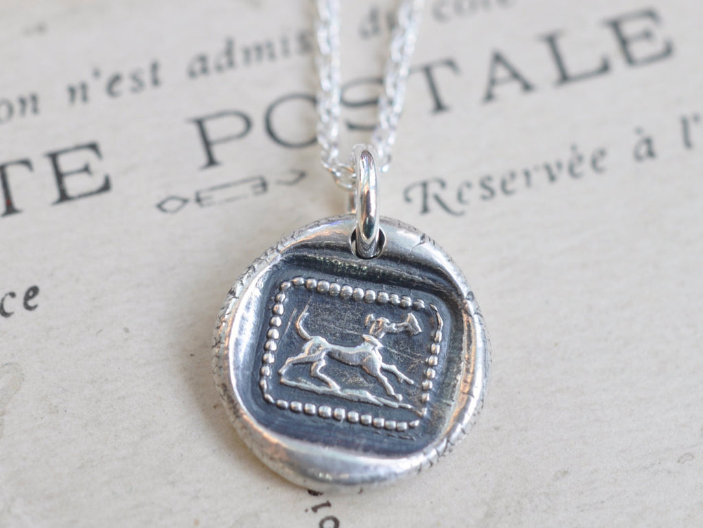 dog carrying a letter wax seal necklace